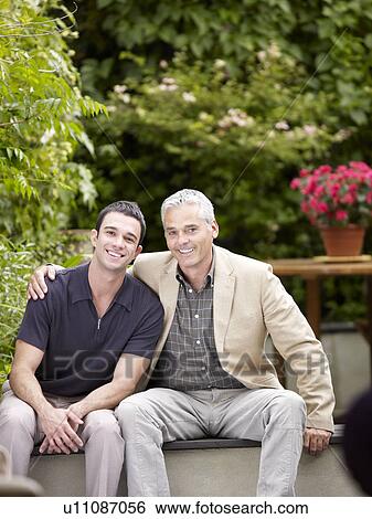 Stock Photograph - Two men sitting in patio facing camera. Fotosearch
