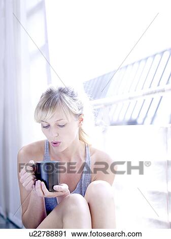 Stock Image - Woman against window with hot drink. Fotosearch