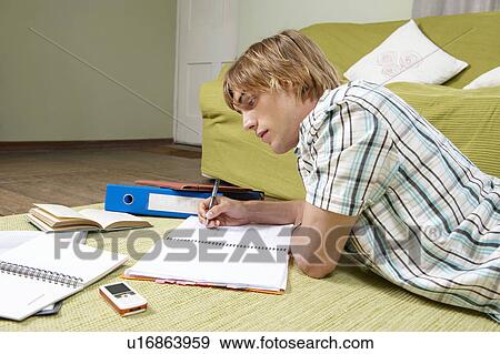 Young man doing home work on rug View Large Photo Image Stock Photo - Young man doing home work on rug. Fotosearch