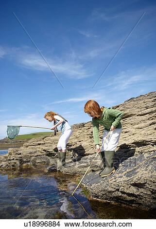 2 girls fishing in rock pool View Large Photo Image Picture - 2 girls fishing in rock pool. Fotosearch