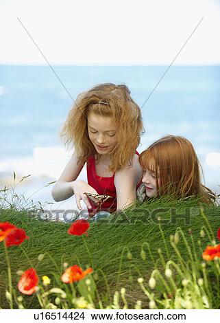 Picture - 2 girls watching butterfly. Fotosearch