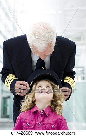 Flight captain fitting hat onto girl View Large Photo Image Stock Photo - Flight captain fitting hat onto girl. Fotosearch