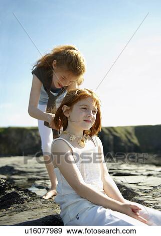 Girl putting shell necklace on sister View Large Photo Image Stock Photo - Girl putting shell necklace on sister. Fotosearch