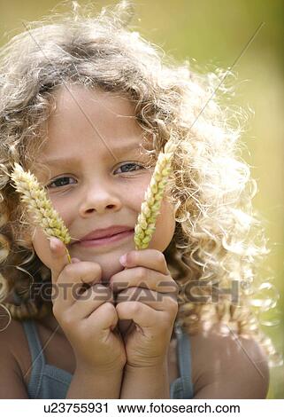 Young girl holds up ears of corn View Large Photo Image Stock Image - Young girl holds up ears of corn. Fotosearch