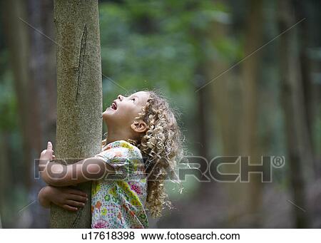 Young girl hugging tree looking up View Large Photo Image Stock Photo - Young girl hugging tree looking up. Fotosearch