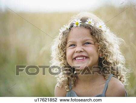 Stock Image - Young girl laughing with daisies in hair. Fotosearch