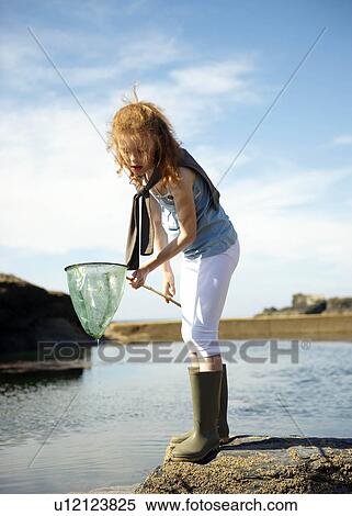 Young girl looking in net at rock pool View Large Photo Image Stock Photography - Young girl looking in net at rock pool. Fotosearch