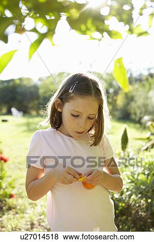 Stock Photo - Young girl outside eating fruit. Fotosearch