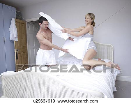 Stock Photo - Man and woman bedroom pillow fight. Fotosearch