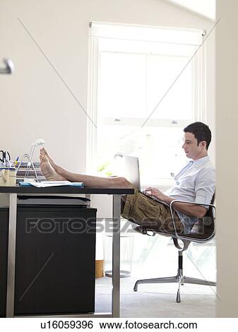 Stock Photograph - Man on laptop in sunny home office. Fotosearch