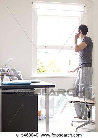 Stock Image - Man on phone in sunny home office. Fotosearch