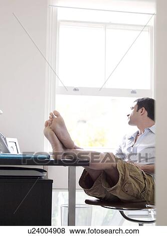 Stock Photo - Man reclining in sunny home office. Fotosearch