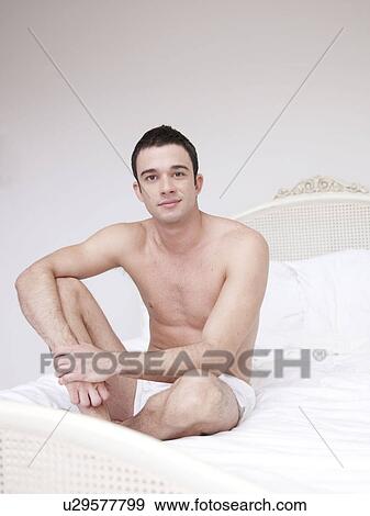 Man sitting on bed View Large Photo Image Stock Photo - Man sitting on bed. Fotosearch