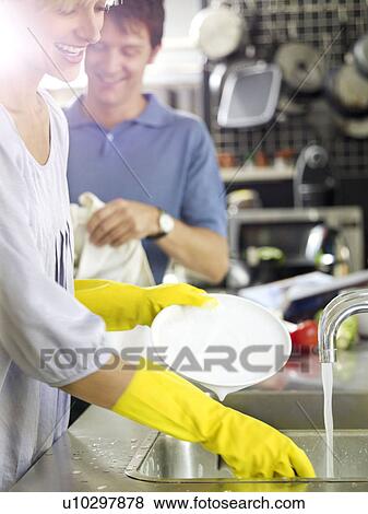 Stock Photo - Woman and man in kitchen washing up. Fotosearch