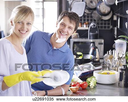 Stock Photography - Woman and man in kitchen washing up. Fotosearch