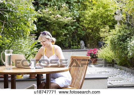 Young woman at garden table on laptop View Large Photo Image Stock Image - Young woman at garden table on laptop. Fotosearch