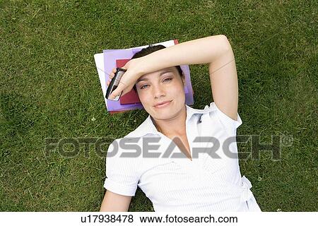 Stock Photo - Businesswoman in grass, holding mobile. Fotosearch
