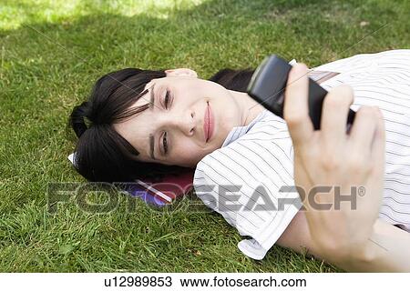 Businesswoman laying in grass, texting View Large Photo Image Stock Image - Businesswoman laying in grass, texting. Fotosearch
