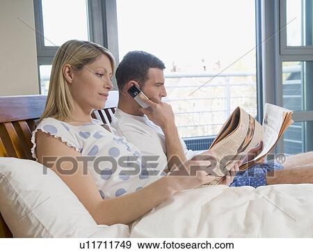 Couple reading financial papers in bed View Large Photo Image Stock Photo - Couple reading financial papers in bed. Fotosearch