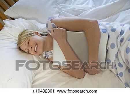 Female hugging her laptop in bed View Large Photo Image Stock Image - Female hugging her laptop in bed. Fotosearch