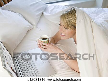 Female working on laptop in bed View Large Photo Image Stock Photograph - Female working on laptop in bed. Fotosearch