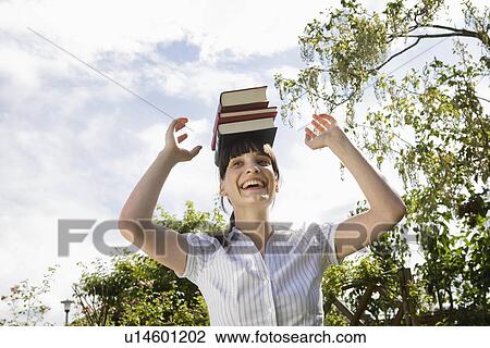 Woman balancing books on head, laughing View Large Photo Image Stock Image - Woman balancing books on head, laughing. Fotosearch