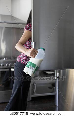 Woman getting milk from fridge View Large Photo Image Stock Photo - Woman getting milk from fridge. Fotosearch