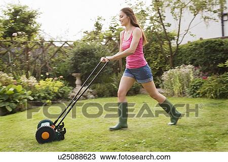 Stock Image - Woman mowing lawn with grass mower. Fotosearch