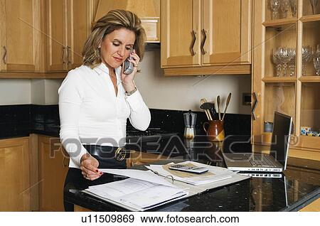 Stock Photo - Woman on phone and looking at papers. Fotosearch