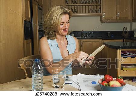 Woman opening letter at kitchen table View Large Photo Image Stock Photo - Woman opening letter at kitchen table. Fotosearch