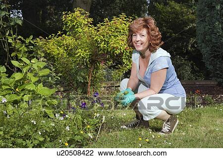 Stock Image - Woman working in garden. Fotosearch