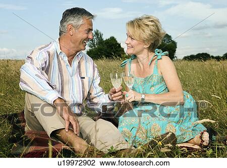 Stock Image - Couple have a picnic in a field. Fotosearch