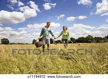 Couple holding hands with dog in field View Large Photo Image Stock Image - Couple holding hands with dog in field. Fotosearch
