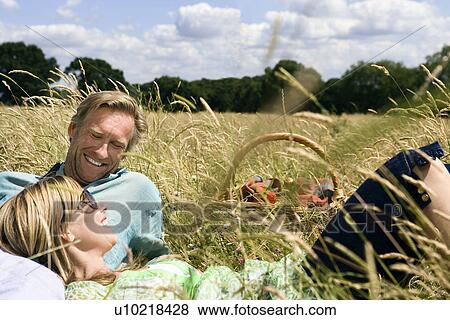 Couple laying field, with picnic basket View Large Photo Image Stock Photo - Couple laying field, with picnic basket. Fotosearch
