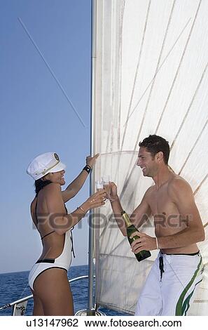 Stock Image - Couple making a toast on sailboat. Fotosearch
