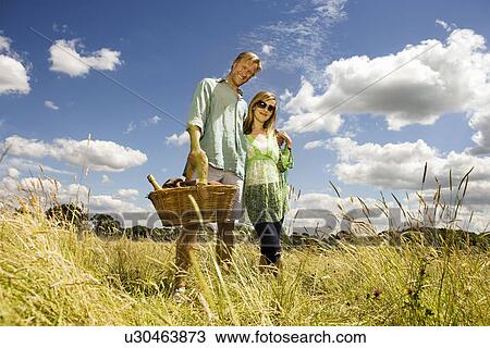 Couple with picnic basket in field View Large Photo Image Stock Image - Couple with picnic basket in field. Fotosearch
