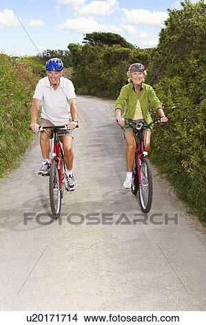 Senior couple cycling on country lane View Large Photo Image Picture - Senior couple cycling on country lane. Fotosearch