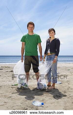 Young couple collecting garbage on beach View Large Photo Image Stock Image - Young couple collecting garbage on beach. Fotosearch
