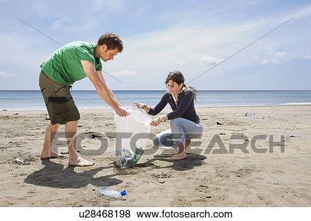 Young couple collecting garbage on beach View Large Photo Image Stock Photo - Young couple collecting garbage on beach. Fotosearch