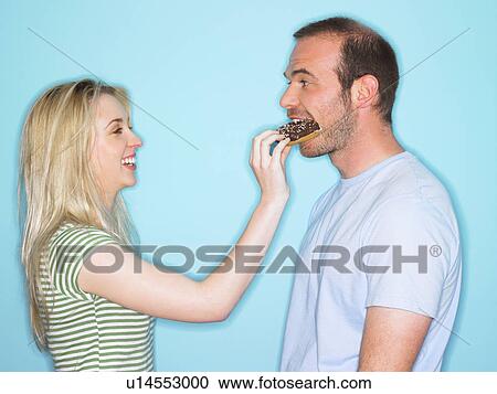 Young woman feeding man with cake View Large Photo Image Stock Image - Young woman feeding man with cake. Fotosearch