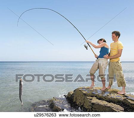 Couple landing a big fish off rocks View Large Photo Image Stock Image - Couple landing a big fish off rocks. Fotosearch
