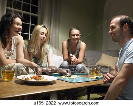 Stock Image - Four young people playing scrabble. Fotosearch