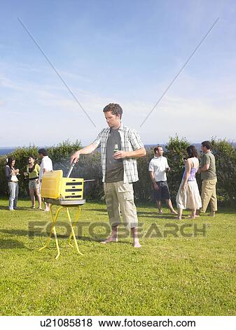 Man tending barbecue at a party View Large Photo Image Stock Photo - Man tending barbecue at a party. Fotosearch