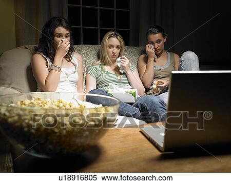 Stock Photography - Three young women watching a movie. Fotosearch