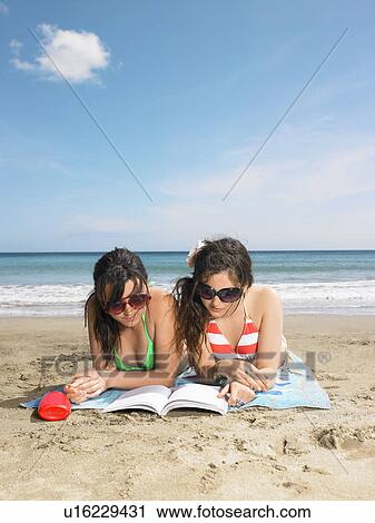 Two young woman sharing a book View Large Photo Image Stock Image - Two young woman sharing a book. Fotosearch