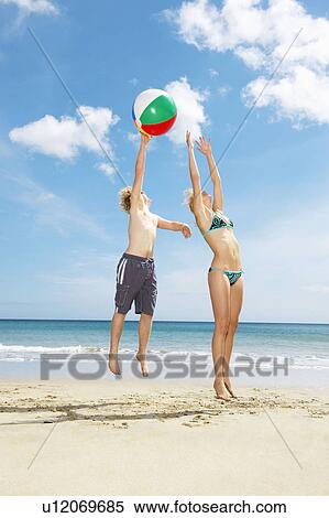 Young couple leaping for beach ball View Large Photo Image Stock Photography - Young couple leaping for beach ball. Fotosearch