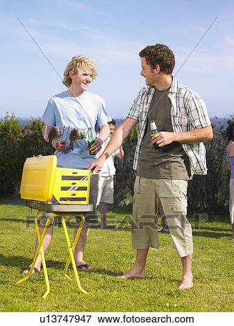 Stock Photo - Young men chatting by barbecue. Fotosearch