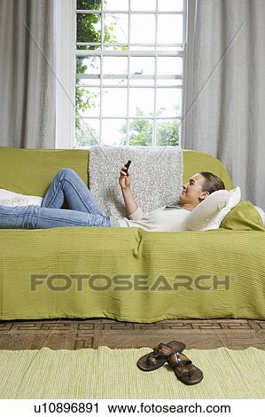 Young woman texting on couch View Large Photo Image Stock Image - Young woman texting on couch. Fotosearch