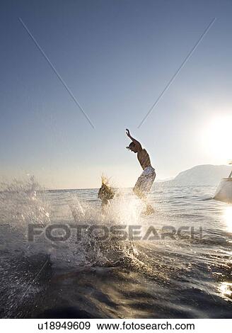 Couple jump off back of sailboat View Large Photo Image Stock Photo - Couple jump off back of sailboat. Fotosearch