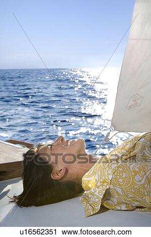 Woman laying in sun on sailboat View Large Photo Image Stock Image - Woman laying in sun on sailboat. Fotosearch